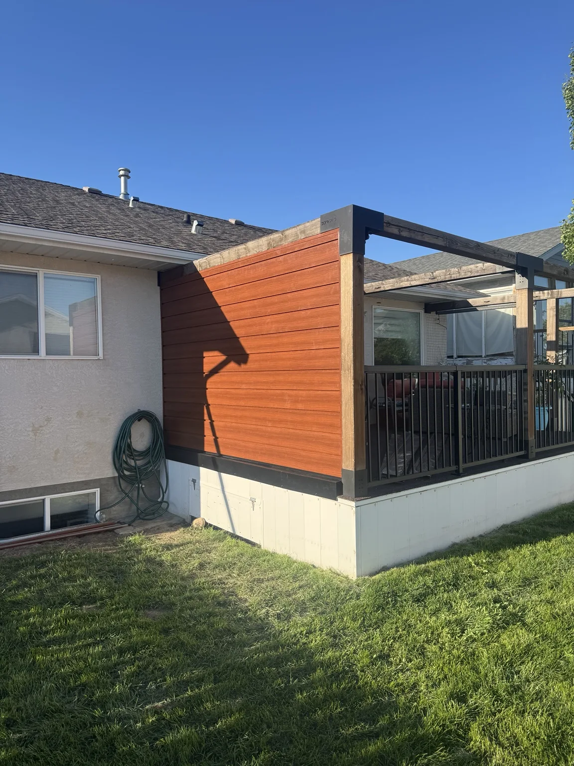 Custom horizontal-clad privacy wall beneath pergola